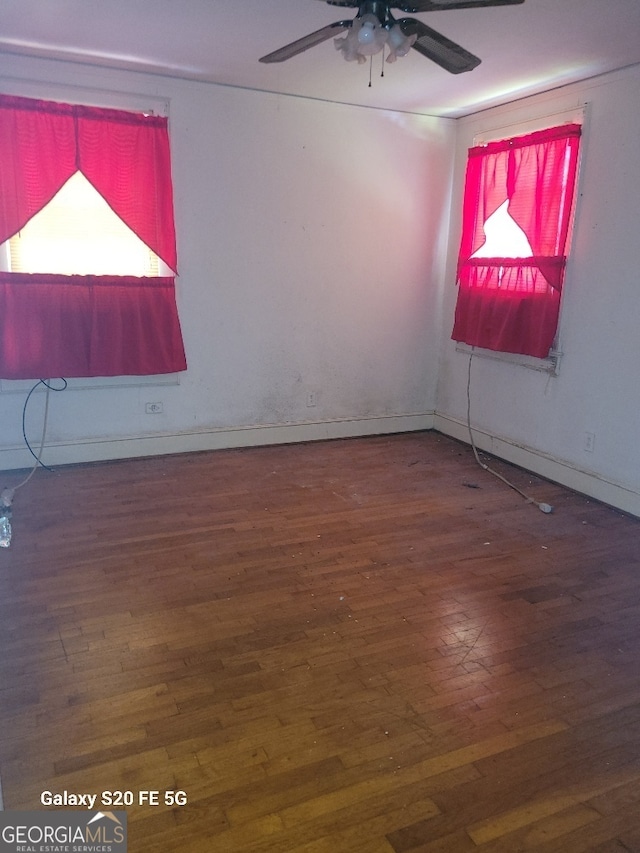 empty room featuring a ceiling fan, baseboards, and wood finished floors