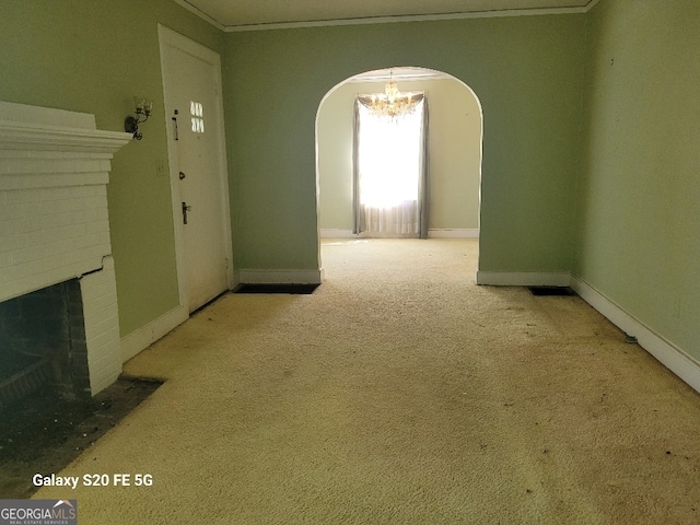 interior space with carpet flooring, a brick fireplace, arched walkways, baseboards, and ornamental molding