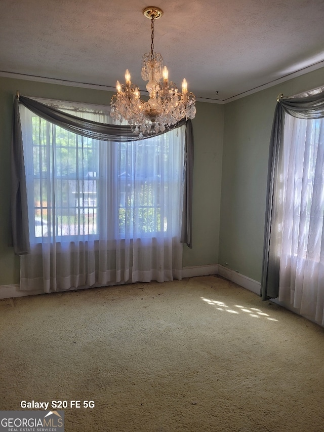 spare room with carpet flooring, baseboards, an inviting chandelier, and ornamental molding