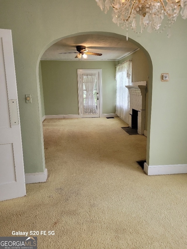 unfurnished living room featuring carpet flooring, arched walkways, and a brick fireplace
