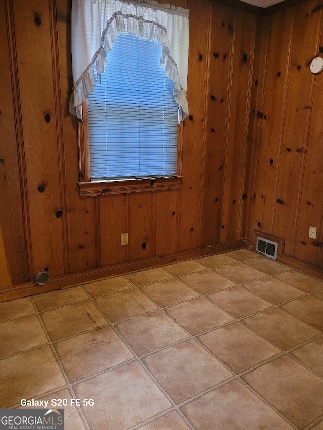 spare room featuring wood walls and visible vents