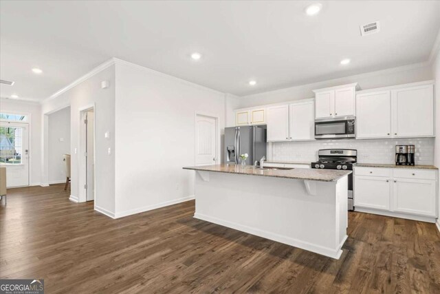 kitchen with stainless steel appliances, ornamental molding, a kitchen island with sink, tasteful backsplash, and light stone countertops