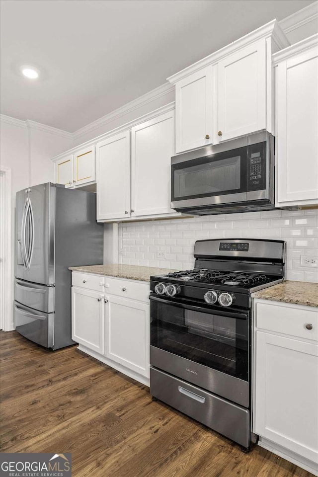 kitchen featuring appliances with stainless steel finishes, white cabinets, crown molding, tasteful backsplash, and light stone countertops