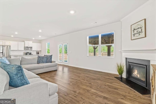 living room with crown molding, dark wood-style flooring, recessed lighting, baseboards, and a fireplace with flush hearth