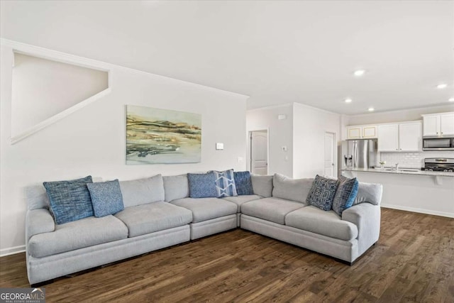 living area with recessed lighting, dark wood-type flooring, ornamental molding, and baseboards