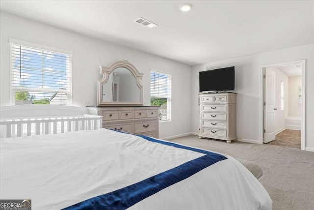 bedroom with light colored carpet, baseboards, and ensuite bathroom