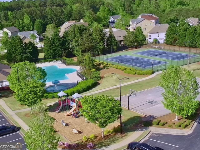 bird's eye view of a pool area and a heavily wooded area