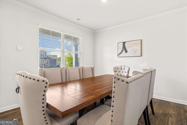 dining room featuring wood finished floors, crown molding, and baseboards