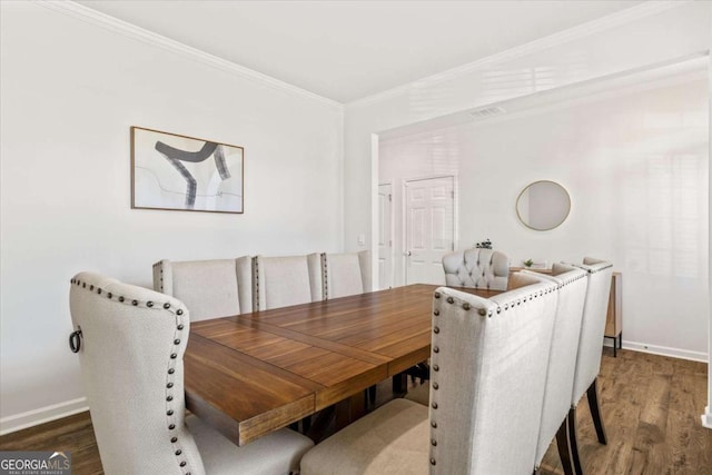 dining room featuring wood finished floors, baseboards, and crown molding