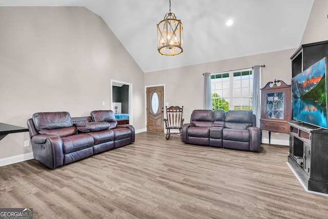 living area featuring an inviting chandelier, wood finished floors, high vaulted ceiling, and baseboards