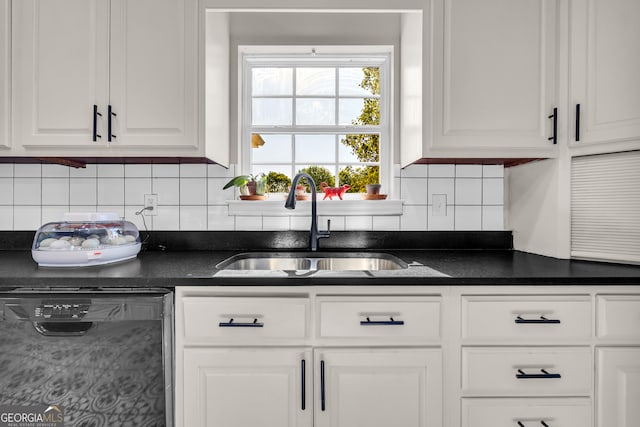 kitchen featuring decorative backsplash, white cabinets, a sink, dark countertops, and dishwasher