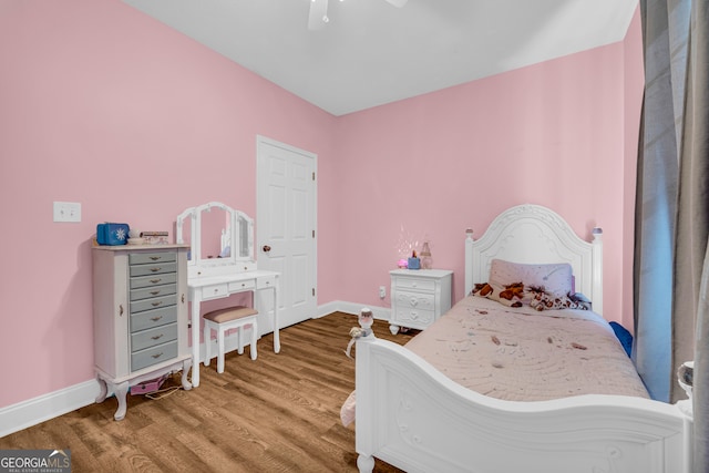 bedroom with ceiling fan, wood finished floors, and baseboards