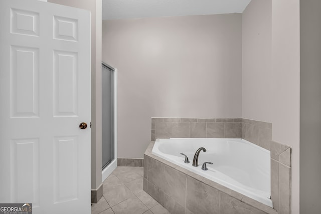 full bathroom featuring tile patterned flooring, a bath, a stall shower, and baseboards