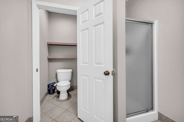 bathroom featuring baseboards, a stall shower, and toilet