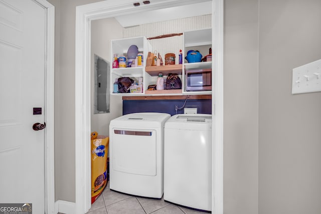 laundry room featuring washing machine and dryer, light tile patterned flooring, electric panel, and laundry area