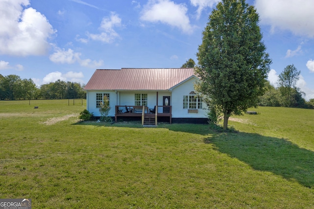rear view of property with a wooden deck, metal roof, and a yard