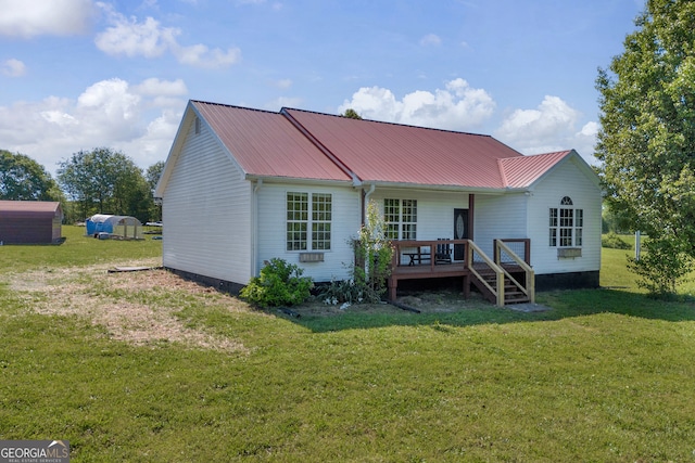 rear view of house with metal roof, a lawn, and covered porch