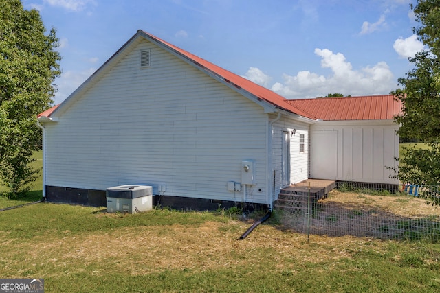 view of side of home with a yard, fence, metal roof, crawl space, and central AC
