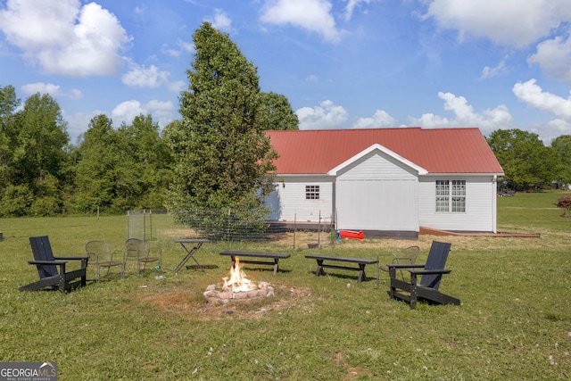 rear view of property with metal roof, a yard, and an outdoor fire pit