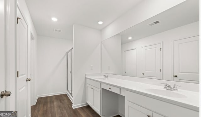 full bathroom with a sink, double vanity, a stall shower, visible vents, and wood finished floors