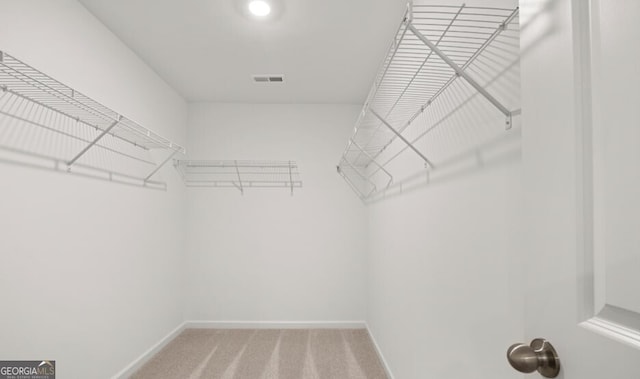 walk in closet featuring visible vents and light colored carpet