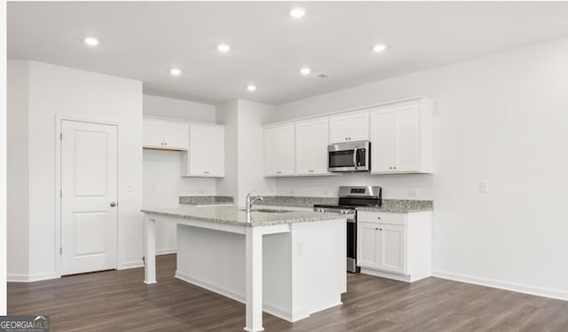 kitchen featuring white cabinets, dark wood finished floors, an island with sink, and stainless steel appliances