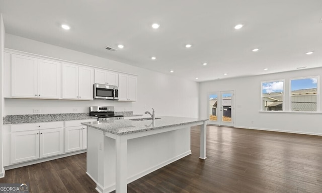 kitchen featuring white cabinets, dark wood finished floors, an island with sink, stainless steel appliances, and a sink