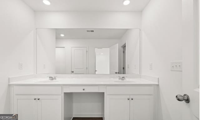 full bath with a sink, double vanity, and recessed lighting