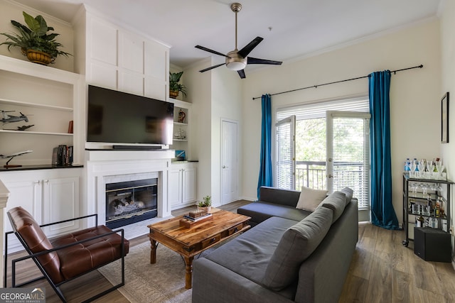 4246 River Green Dr Unit 202, Atlanta, GA 30327 - living room featuring a glass covered fireplace, a ceiling fan, crown molding, wood finished floors, and built in features