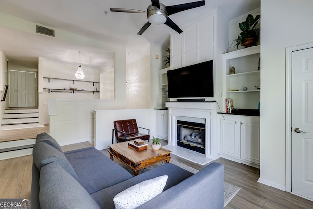 4246 River Green Dr Unit 202, Atlanta, GA 30327 - living room featuring a ceiling fan, wood finished floors, a glass covered fireplace, and built in features
