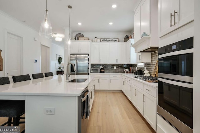 kitchen featuring a kitchen breakfast bar, a sink, crown molding, decorative backsplash, and appliances with stainless steel finishes