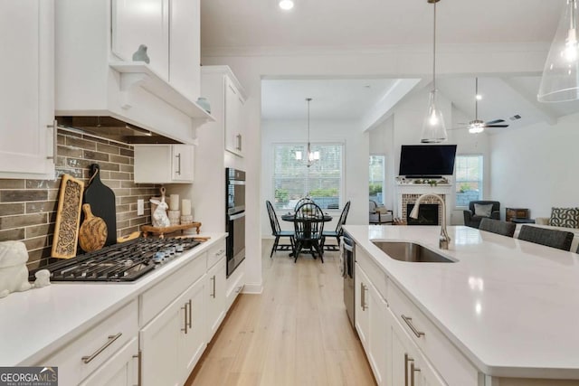 kitchen with stainless steel appliances, a kitchen island with sink, a sink, tasteful backsplash, and a brick fireplace