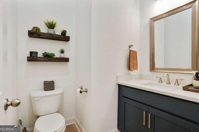 bathroom featuring baseboards, toilet, and vanity