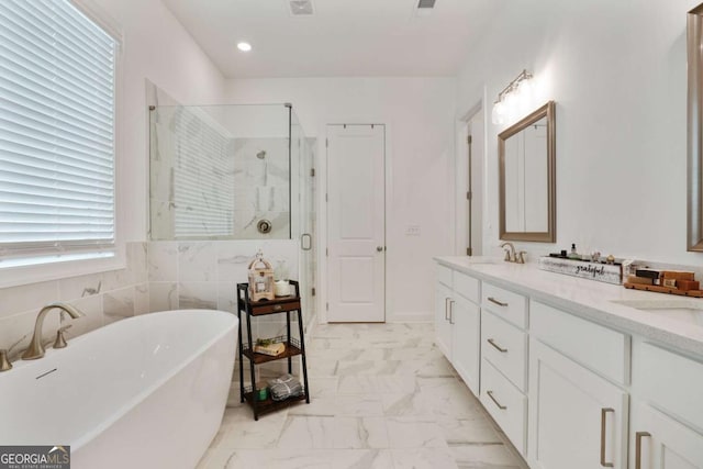 bathroom with marble finish floor, double vanity, a sink, a soaking tub, and a stall shower