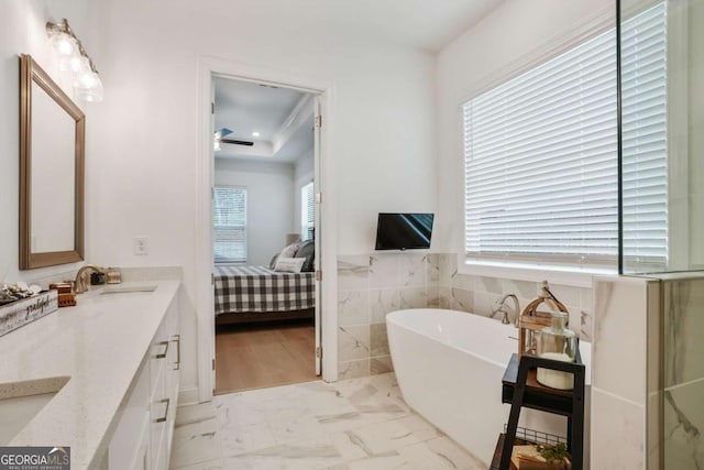 ensuite bathroom with double vanity, a ceiling fan, a sink, ensuite bath, and a soaking tub
