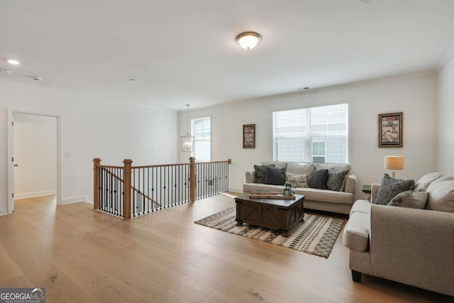 living room with a chandelier, baseboards, and light wood-style floors