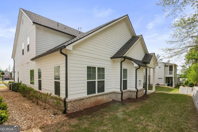 view of side of home featuring a yard and a shingled roof