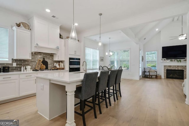 kitchen featuring a fireplace, light countertops, white cabinets, and open floor plan