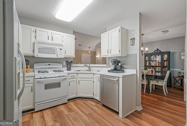 kitchen with light countertops, a sink, white appliances, and light wood-type flooring