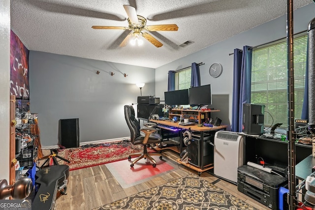 office space featuring ceiling fan, wood finished floors, a textured ceiling, and visible vents