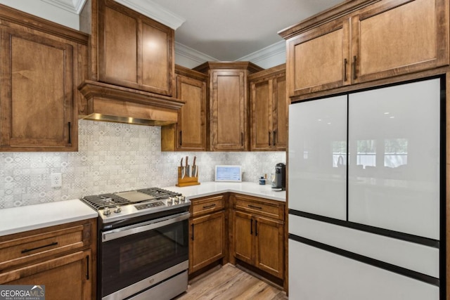 166 Verano St, Kingsland, GA 31548 - kitchen with freestanding refrigerator, stainless steel range with gas stovetop, crown molding, tasteful backsplash, and light countertops