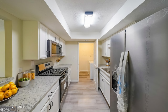 1206 Canyon Point Cir, Roswell, GA 30076 - kitchen with light wood-style flooring, washer and clothes dryer, white cabinetry, light stone countertops, and appliances with stainless steel finishes