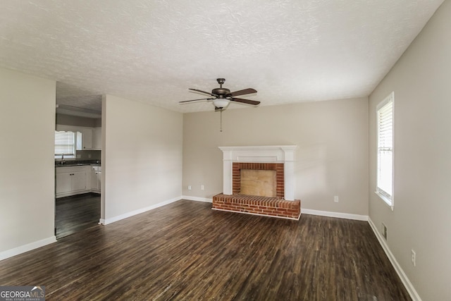 6024 S Deshon Ct, Lithonia, GA 30058 - unfurnished living room with dark wood-type flooring, a ceiling fan, a textured ceiling, and a fireplace