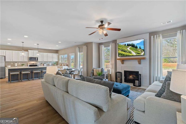 living room featuring ceiling fan, light wood-type flooring, and plenty of natural light