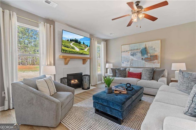 living area with light wood-style flooring, visible vents, and plenty of natural light
