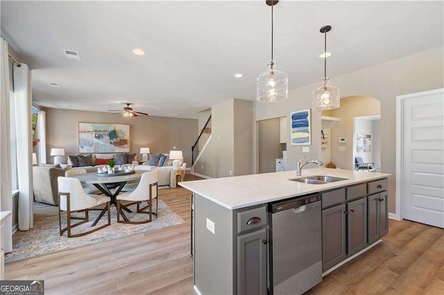 kitchen featuring light wood finished floors, a ceiling fan, stainless steel dishwasher, a sink, and arched walkways