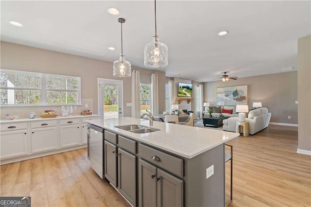 kitchen featuring stainless steel dishwasher, a ceiling fan, a sink, gray cabinets, and light countertops