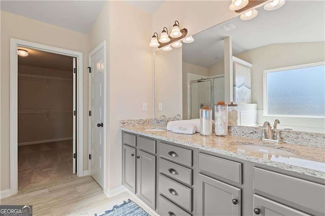 full bath with a shower stall, wood finished floors, double vanity, and a sink