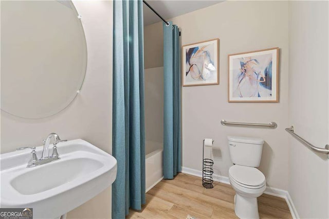 full bath with shower / bath combo with shower curtain, wood finished floors, a sink, and toilet