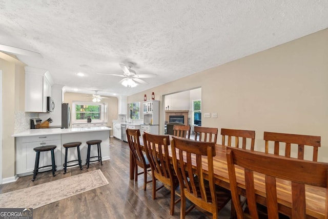 dining area featuring ceiling fan, dark wood-type flooring, and a textured ceiling